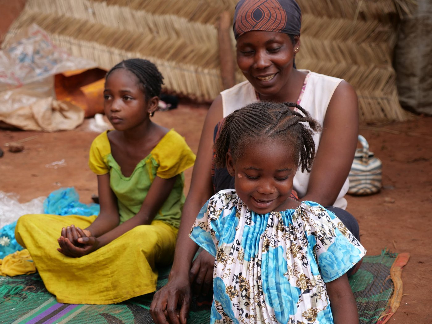 Oumou and Awaou sit with their mother Roukaya in the compound of their house in Berberati.