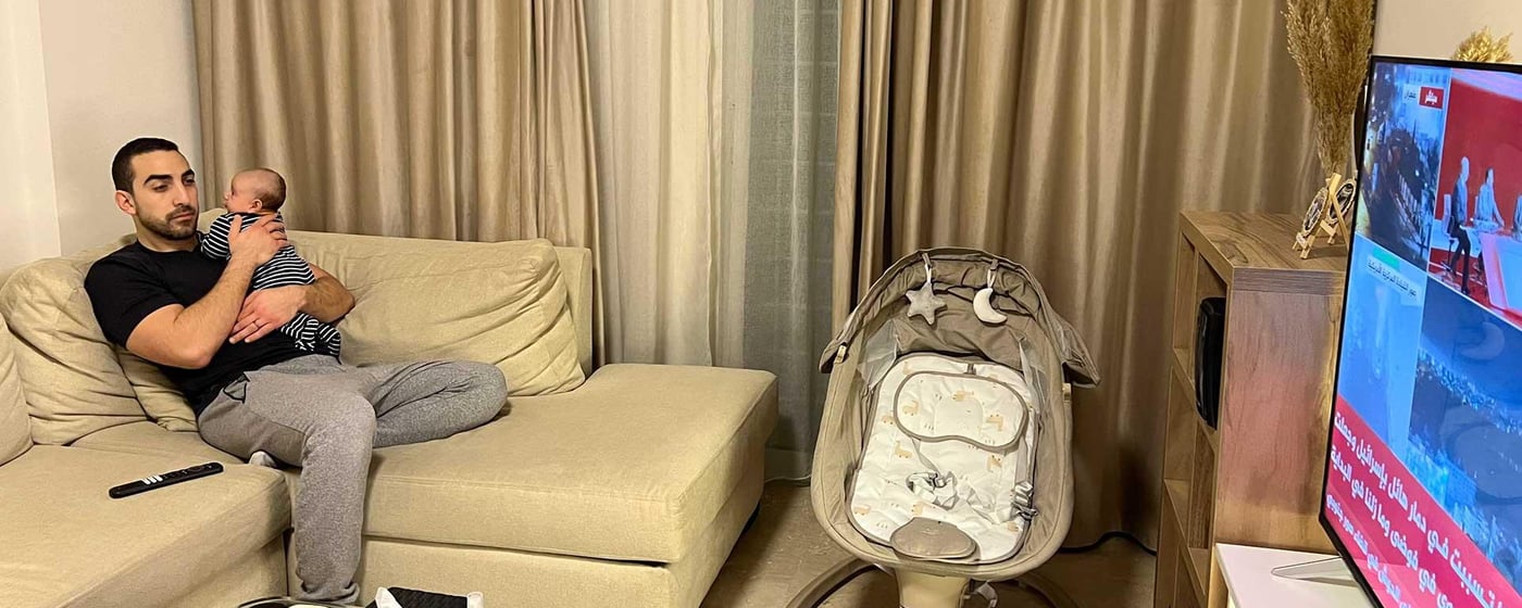 En pappa och hans bebis tittar på nyheterna hemma.