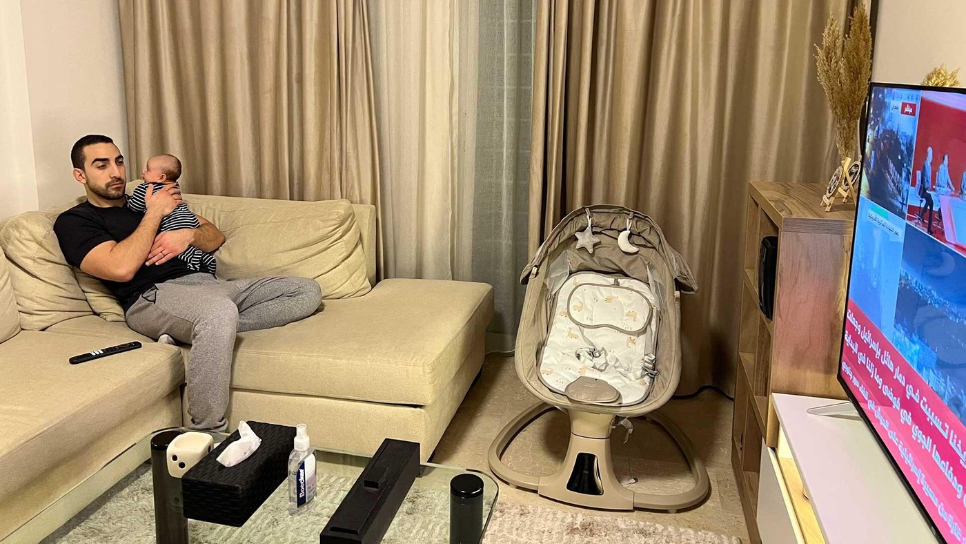 En pappa och hans bebis tittar på nyheterna hemma.