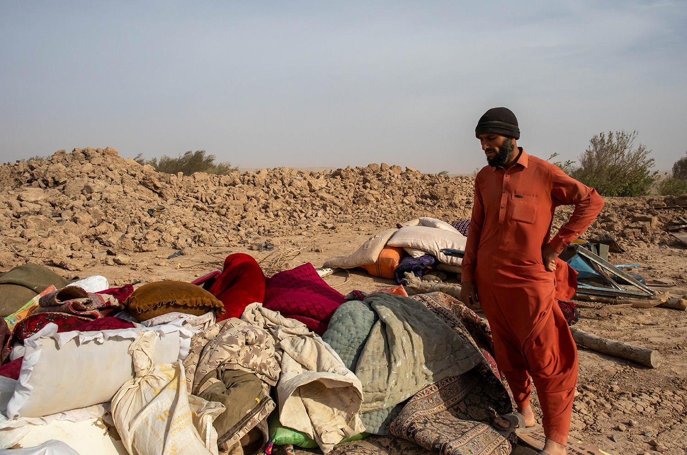 A man is looking at his belongings, which are strewn all over the ground after an earthquake.
