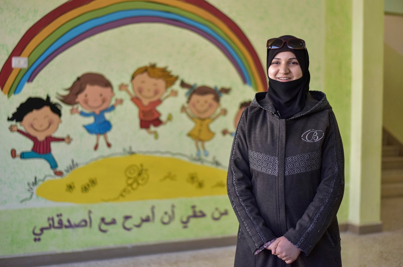 Manal (35) teacher from Harasta
“My son is in the 1st grade. Last year going to school was his least favorite thing to do, every morning he would cry and say that the school building is ugly and damaged. However, for me what mattered the most is that despite the classrooms lacked windows, doors and debris were scattered everywhere, inside it, there were a teacher who is working hard to educate the students and support them.
Thankfully, after the rehabilitation of the school by NRC, my son’s spirits are lifted and he is happier more than ever. Every night, he prepares his books, school uniform and the equipment needed to participate in the activities, which I and other teachers learned in the teacher training in summer. The new shape of the school, the beautiful drawings on the wall and the new way of teaching is what I like the most. Now I can better understand the child’s psychology, how to put myself in his shoe, to know his needs and feelings and in return deliver him the information through creative learning activities and new techniques.”
I value this noble profession because I can support my students and the whole community through the children, who are the core element of building the future of Syria.”
Photo: Tareq Mnadili/NRC