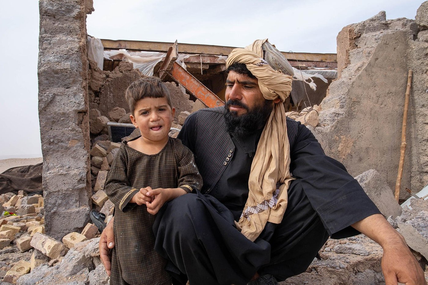 Father and son in front of their ruined home.