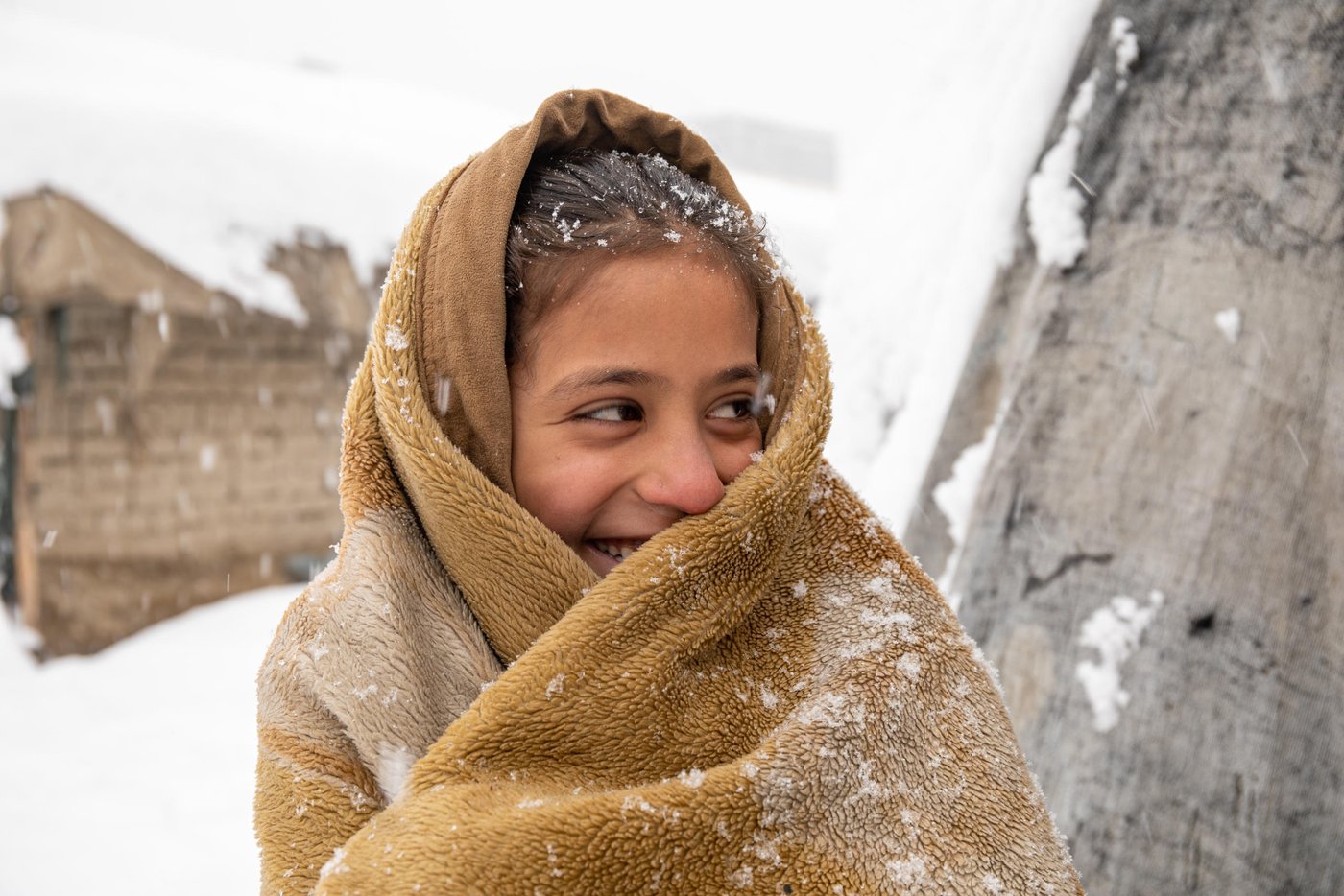 “It was very cold inside and I thought if I go outside and walk I might feel warmer,” says Roqia, 11, standing outside her makeshift home in a snowy day in KABUL.
Rogia doesn’t have enough clothes and proper slippers to keep her warm in a cold. Her family do not have sufficient firewood to keep the oven burning all the time and they only burn it once in a day and if the weather is freezing cold, they might burn it twice in a day. They burn plastics, cartons, packets and other waste materials they have collected during the summer season.
“The house we have is out of plastic bags, blankets and mud. As soon as the oven dies the home gets cold,” she says. “It’s very cold during the night and we wakeup many times due to cold. Sometimes, I feel pain and burn in my feet, legs and back due to the cold.”
Kabul gets very cold during the winter and last night only, the temperature dropped to -16 Celsius. Photo: Enayatullah Azad/ NRC