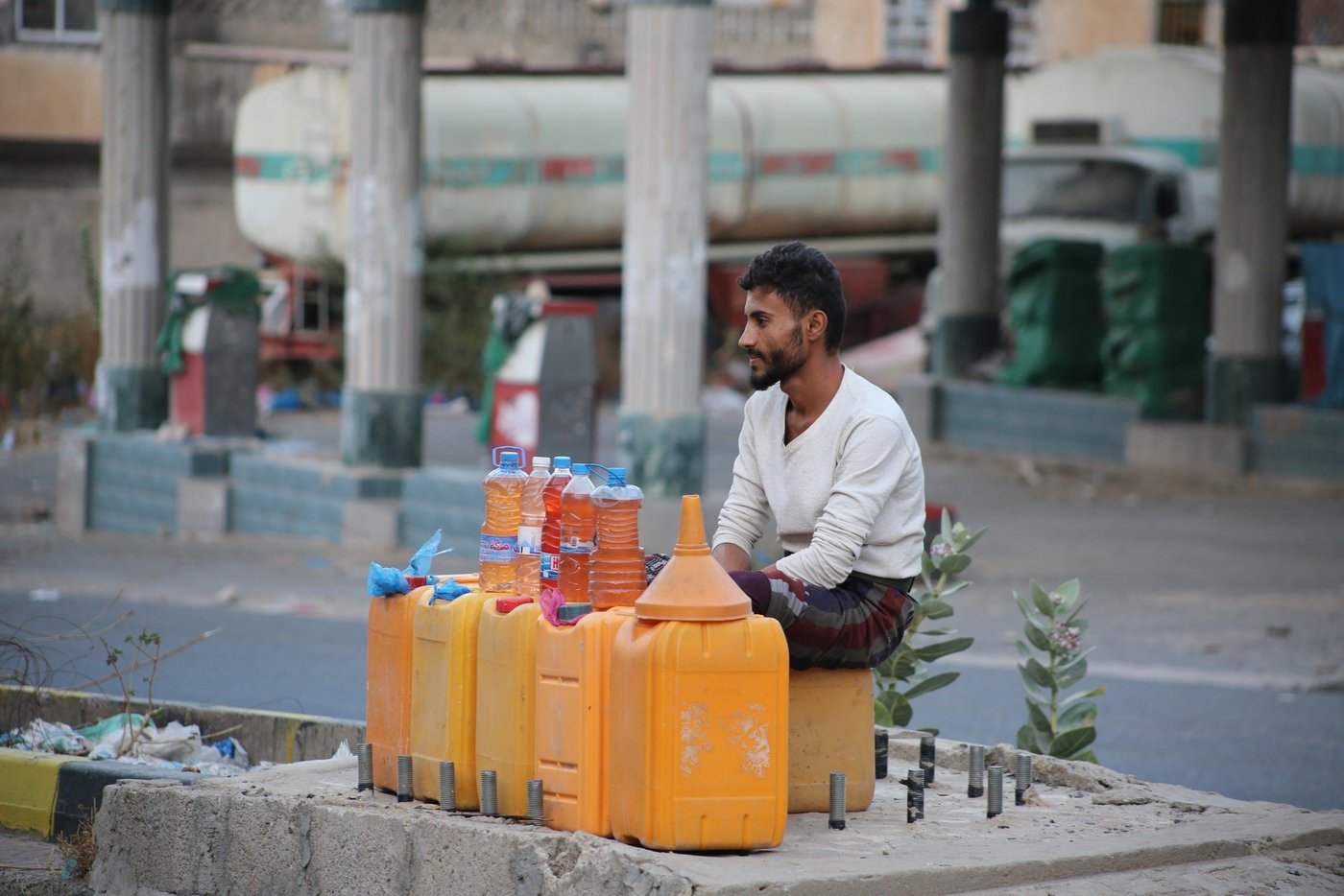 Mohammed Qaid, 20-years old, sells fuel in Taiz city near a closed petrol station. Fuel shortages are common in Yemen and affect cars, hospital generators, and water pumps. Petrol on the black market can be sold for more than two times the official price. "Before the war, I was a student and didn't know anything about fuel. There was no black market. Now I sell fuel on the street. When stations are closed, people depend on the black market to refill their cars and motorcycles". 

Photo: Khalid Al-Banna / Norwegian Refugee Council