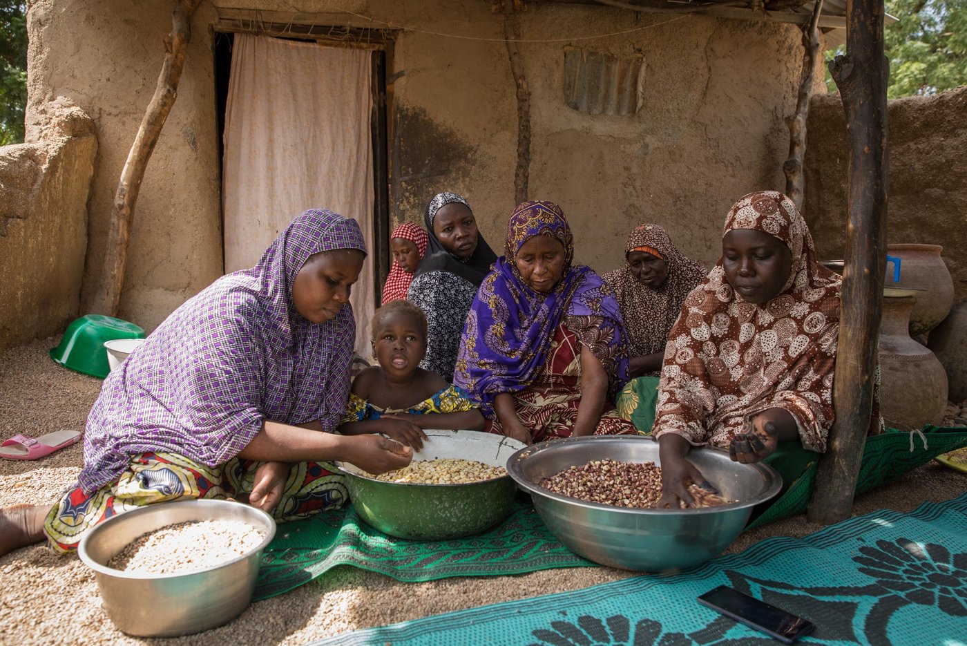 Halima is helped by Gona and her family to prepare the nuts for sale.
The night Boko Haram attacked Halima’s village, her husband disappeared in the chaos and she had to flee alone with her four young children. Five years have passed and she has still not heard from him. She fears he was killed that night.
Halima, 32, is not the only one that has been forced to flee her home because of attacks from armed groups in the border areas between Cameroon and Nigeria. The Boko Haram conflict in Nigeria has led to significant protracted displacements in Cameroon’s Far North region, ranking Cameroon as the second most affected country (after Nigeria) in the Lake Chad Basin region. 64% of all humanitarian needs in the country, affecting approximately 2.1 million people, are concentrated in the Far North region. This includes 227,581 internally displaced persons (IDPs), 92,238 returnees (former IDPs), 96,727 Nigerian refugees, 406,700 host community members and more than one million other vulnerable people (Humanitarian Response Plan - HRP 2018). As more and more attacks are now also happening inside of Cameroon, it is leading to more insecurity and secondary displacements. For aid agencies, access is also increasingly difficult.
“After I fled my home, we stayed in Kourgui for two months hoping that life would be better there, but it was not easy at all, so I decided to come here to Mora".
Mora is a little bit further from the border and feels a bit safer. Halima now rents a small house in a compound with another family, trying to make a new life after having lost all she once owned. Back home she had a sewing machine that gave her a steady income. Without her machine or her husband’s help, she has struggled to make ends meet. Now, with the support from NRC, her situation has turned for the better.
Halima is part of a group of women that are selected for a fish farming project that NRC supports as part of our Food Security activities. A local entrepeneur, Boucar Adji, had set up a fish farming cooperative and NRC decided to provide financial support to this great initiative. The entrepreneur used the funds to expand the fish activities and intentionally hired displaced women to work with him at the cooperative. The women receive 15,000 francs every month from the cooperative for the work they do on the fish farm. Every morning for the past three months, Halima and the other members of the association meet to feed the fish and clean the premises.
In addition, NRC has provided financial assistance directly to the women to help them start up a small business. With the first of three cash instalments, Halima chose to buy peanuts that she now roasts and sells. The income from this and the work at the fish farm has made it possible for her to pay the school fee for two of her four children. It also generates a welcome addition of fish into their diet.
"If today my small family manages to eat fresh fish, it is thanks to the fish farming done by the association," Halima ends.
Photo: Ingebjørg Kårstad/NRC