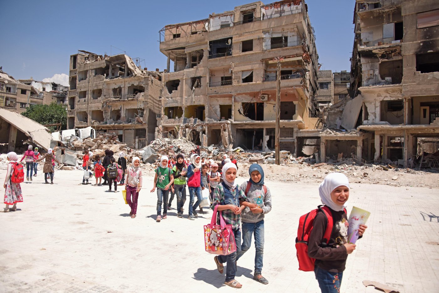Children living in Harasta, Eastern Ghouta, flock to school to catch up on years of missed education. Years of siege ended with a peak in fighting last March. With most of the neighbourhood in ruins, tens of thousands of Syrians are still displaced with no home to return to, but hundreds have also returned to what remains of their houses or stayed all along.
Despite all they have been through, these children are happy to be back to school. This one in Harasta houses 725 children, with parts of it completely destroyed and others badly damaged.
Photo: Karl Schembri/NRC