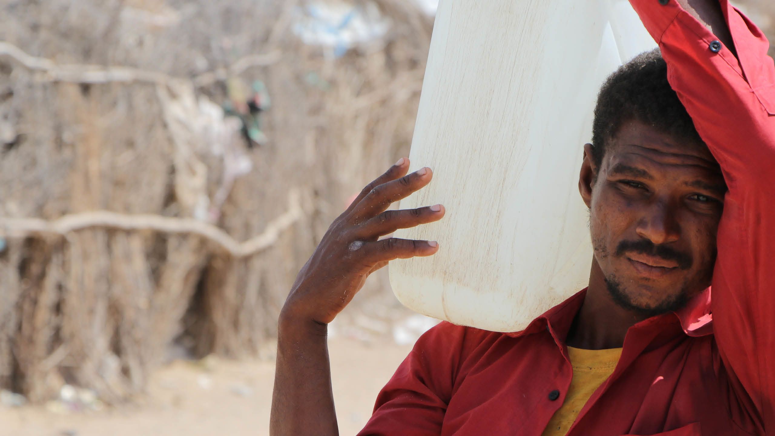 Ein Mann, der eine Dose Wasser auf der Schulter trägt